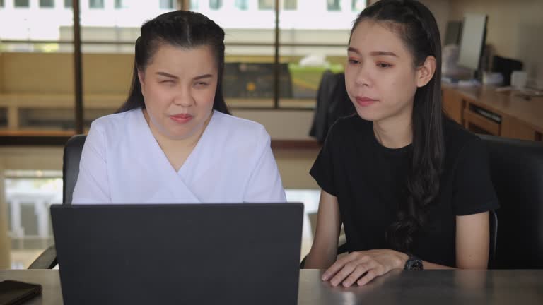 Asian women co-workers in workplace including person with blindness disability using laptop computer with screen reader program for visual impairment people. Disability inclusion at work.