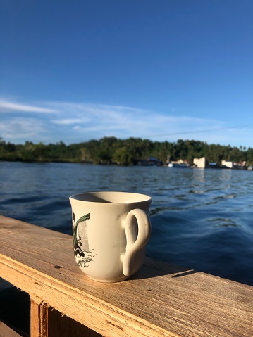 Central Sulawesi, Indonesia - April 23, 2023 : enjoying the morning with a cup of coffee by the beach