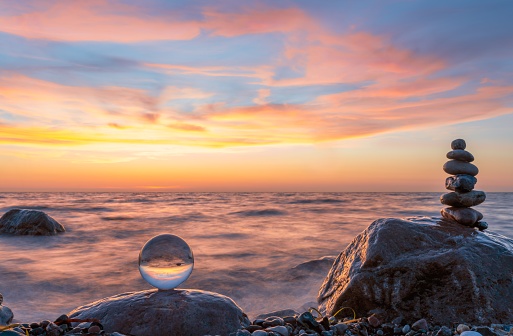 Stone pyramids and glass sphere on the dreamy Baltic Sea sand beach on Rügen for the spectacular sunset