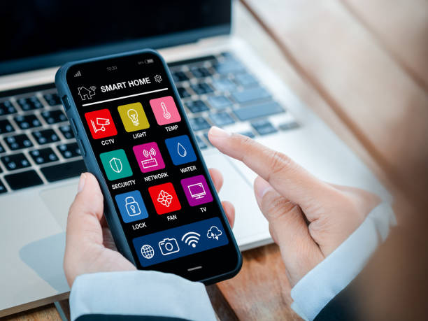 istock Smart home applications technology on smartphone holding in hand. Smart house app screen on mobile phone for wireless remote connection control using by business person who working with computer. 1486531484
