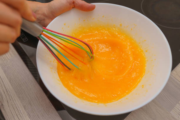 istock Preparing a delicious dessert: Hands whisking eggs in a white glass bowl 1486535124