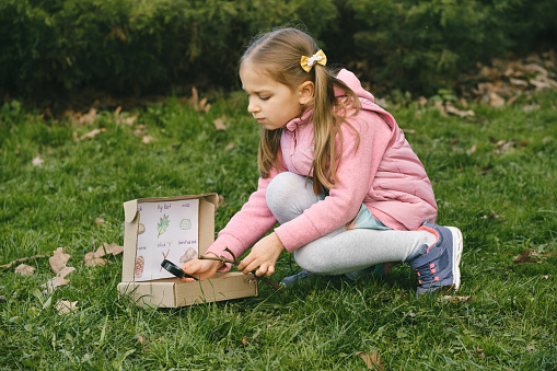 Scavenger hunt for kid in the park. Girl learning about environment. Natural education activity for World Earth day. Exploring in spring.