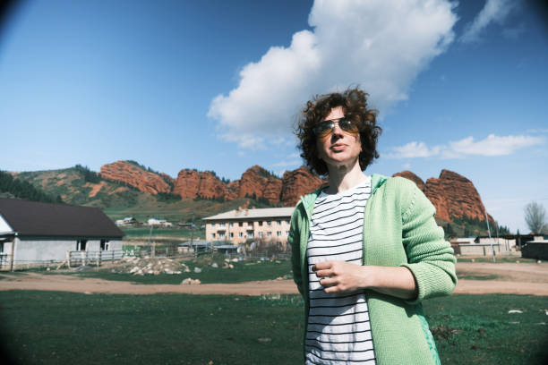 Female backpacker is looking around in remote village at red rock mountains