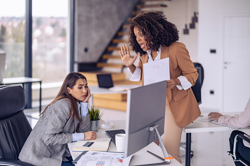 Angry boss yelling at her employee, she is stressed and feeling frustrated on work.Young ambitious female boss yelling at new unhappy female employee.Mobbing at work.