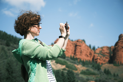 Female backpacker is using phone to take pictures while exploring mountains