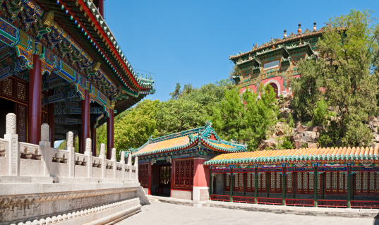 The vibrant ornate pavilions of the historic Summer Palace in Beijing overlooking quiet shaded patio and marble bridges under the distinctive pagoda of Tower of Buddhist Incense (Fo Xiang Ge) on Longevity Hill. ProPhoto RGB profile for maximum color fidelity and gamut.
