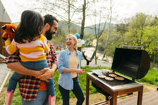 Photo of a multiracial family preparing delicious burgers while celebrating the Fourth of July in their yard