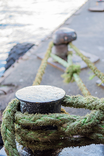 yellow bollard harbor on boat pier with green sea rope