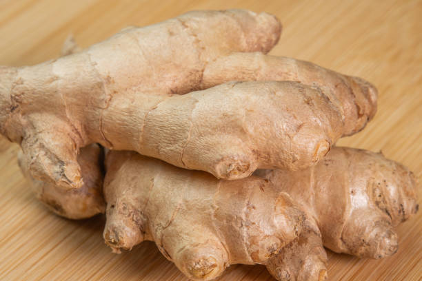 radice di zenzero intera fresca su sfondo di legno da vicino. condimento per spezie ed erbe aromatiche per cucinare. erbe medicinali. uso di zenzero a fette in aromaterapia. alto contenuto di oli essenziali nella pianta - ginger root ingredient nature foto e immagini stock