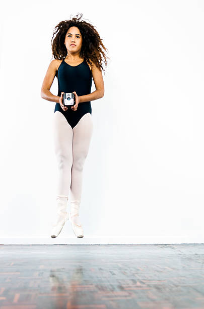 Young female ballerina taking a picture with a vintage camera in pose
