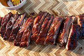 A rustic wooden cutting board displays a mouthwatering rack of barbecue pork spare ribs at a backyard barbecue, sliced and ready to serve, tempting the taste buds.