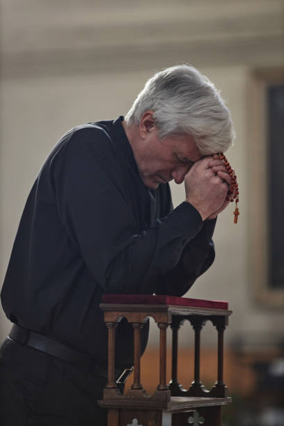 istock Senior man with roast beads praying in church 1486567475