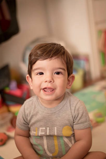 istock Cute little boy looking at camera while sitting on the floor at home. 1486571108