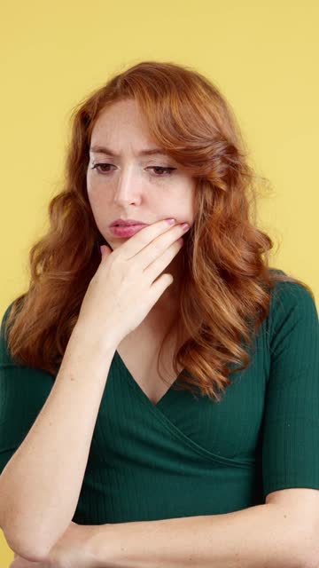 Redheaded woman with hand on face and thoughtful expression