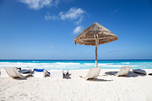 Caribbean sea coastline with grass sun umbrella and wooden beach beds. Vacation concept