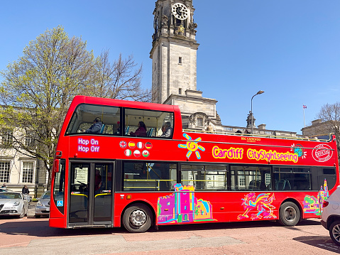 Cardiff, Wales - April 2023: Hop on hop off tourist sightseeing bus taking visitors on a tour of the city