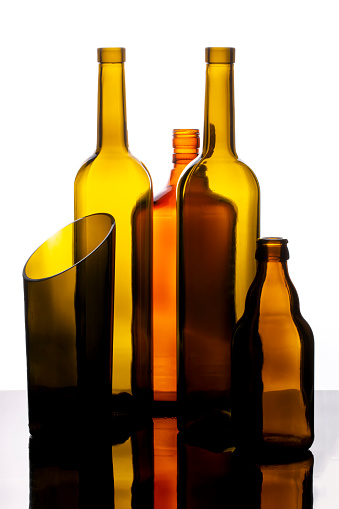 Three empty glass bottles with cork insert in a line on a white background.