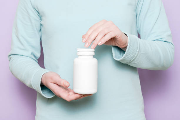 istock White plastic bottle in female hand. Packaging for pills, capsules or supplements. 1486582263