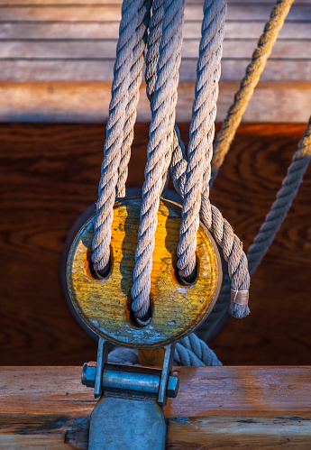 A wooden pulley with a rope on vintage sailing boat rigging.