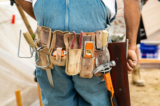 Tool belt on masonry construction worker wearing coveralls