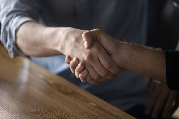 istock Close up of business greeting handshake over office work table 1486590121