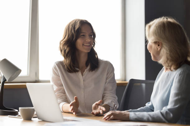 istock Two cheerful different aged business colleagues chatting at work table 1486590125