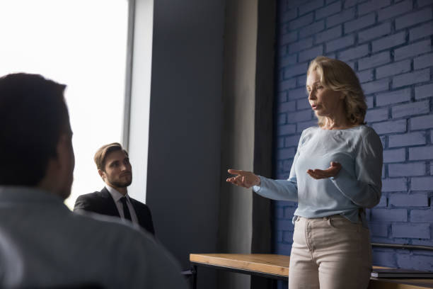 istock Serious elder mature business coach woman presenting seminar to group 1486590143