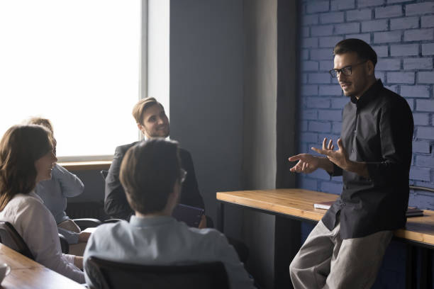 istock Serious handsome young business project leader talking to team 1486590952