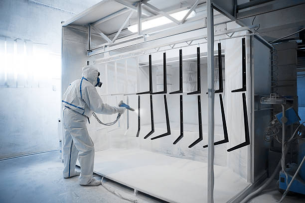 Powder coating  in a special camera Worker wearing protective wear performing powder coating of metal details in a special industrial camera talcum powder stock pictures, royalty-free photos & images