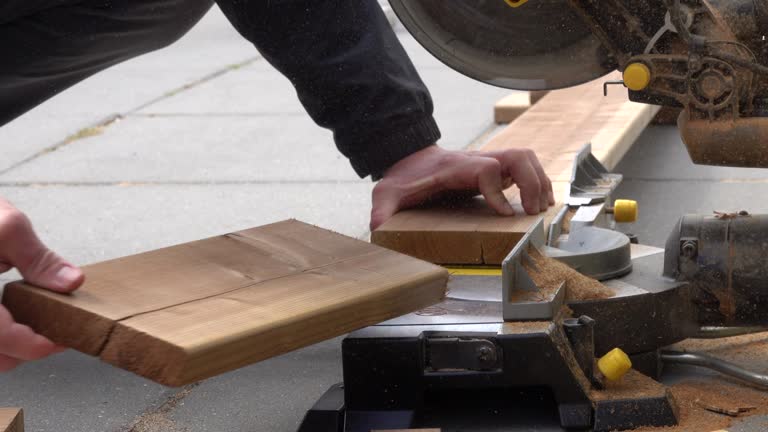 Man working with circular blade saw for cutting wood beam.