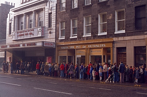 Edinburgh, Scotland, UK, 1977. Cinema Sunday in Edinburgh. Parents with their children are queuing in front of the cinema box office to see the film \