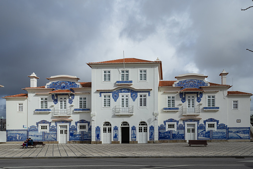 Beautifully decorated historical train station with blue portuguese azulejos tiles, people sitting on a bench