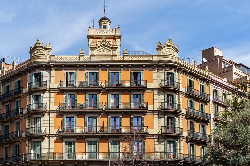 A low angle view of a modernist building in Barcelona, Spain, with its grand facade windows against the sky of an estate neighborhood.