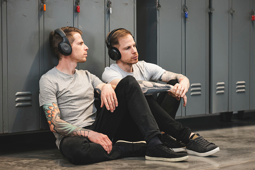 twin brothers wearing headphones, sitting, chilling, listen to music.