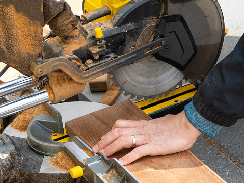 Man working with circular blade saw for cutting wood beam. Close up image of hand power tools.