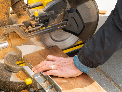 Man working with circular blade saw for cutting wood beam. Close up  image of hand power tools.
