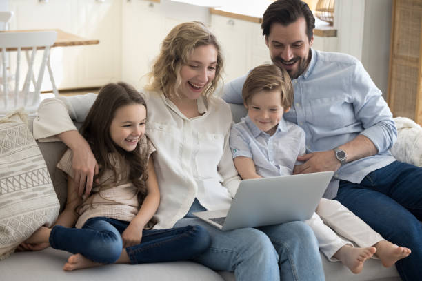 istock Excited parents and two happy little kids using laptop 1486601370