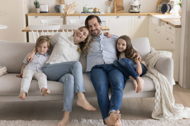 istock Happy mom, dad and two little kids resting on couch 1486602419