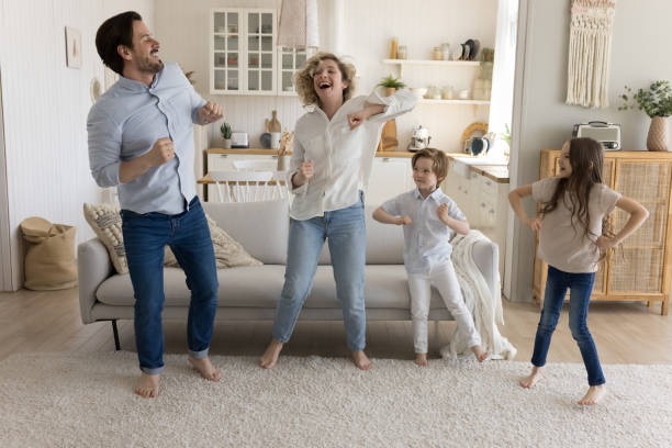 istock Joyful mom, dad and two little kids dancing at home 1486602423