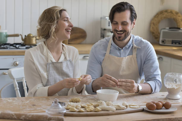 Cheerful couple in love in aprons baking in home kitchen