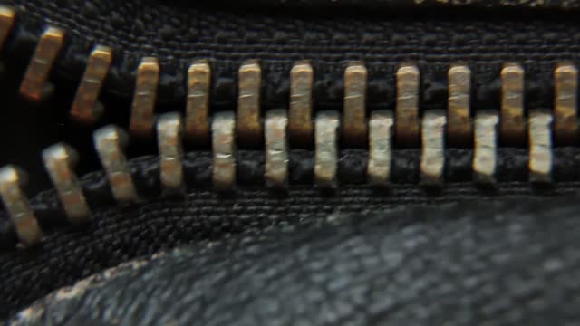 Close-up of a vintage metal zipper on a leather jacket.