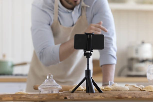 istock Male baker preparing pastry food, speaking at smartphone webcam 1486606384