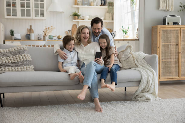 istock Cheerful mom, dad and two little kids using mobile phone 1486606889