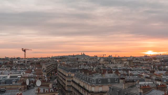 Sunrise above Paris rooftops, warm colorful sky,  Sacre Coeur Basilica on the horizon, early morning time lapse, France