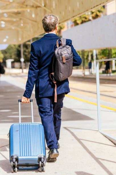 istock Elegant businessman checking email on mobile phone while walking with suitcase inside airport 1486611517