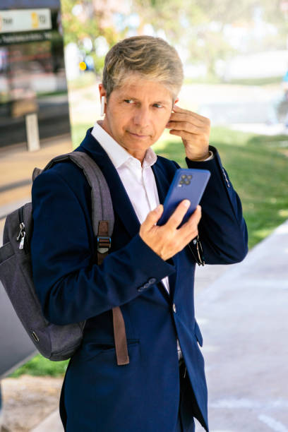 istock Middle-aged businessman dressed in suit and executive backpack wearing wireless headset with phone. 1486611524