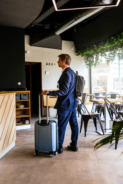 istock Middle-aged businessman dressed in suit, executive backpack and suitcase waiting in a bar 1486611545