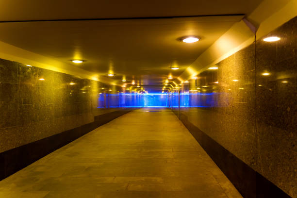 The underpass with granite walls is illuminated by yellow lamps