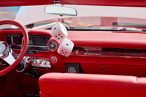 Fuzzy dice dangling from the rear view mirror of the vintage auto