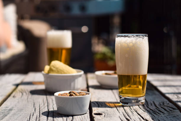 istock Two beer glasses, chips and pistachio nuts on patio table 1486620036